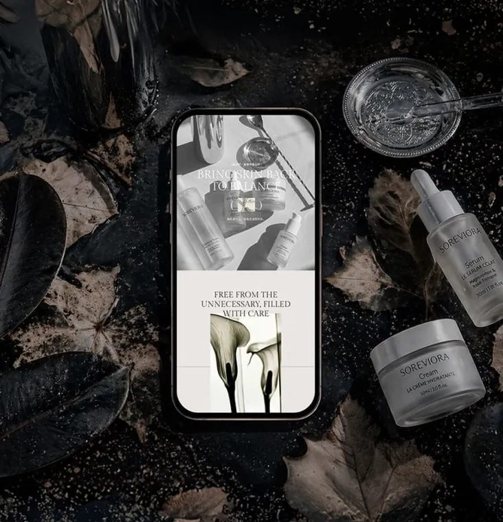 Skincare brand site on a phone, product hero over a dark botanical still life