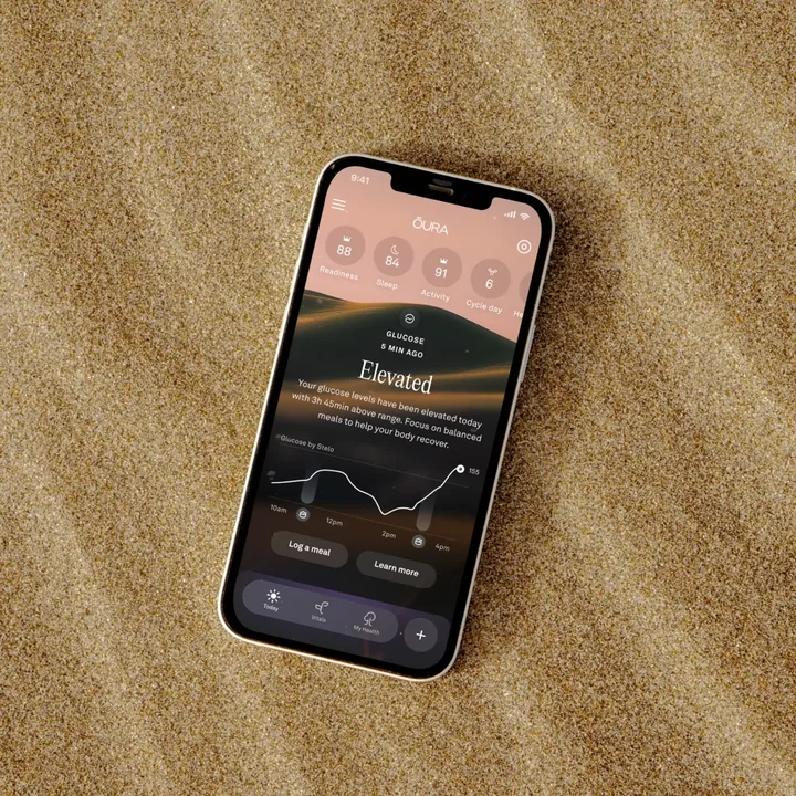 Smartphone on rippled sand showing a health-tracking app interface